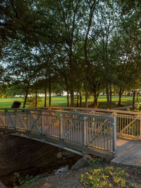 Red Oak, TX with a green park with a bridge and lots of mature trees